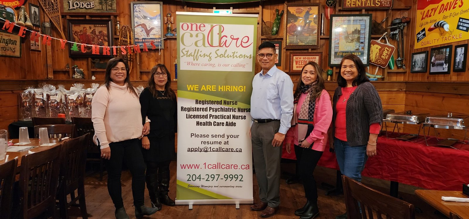 One Call Care Staffing Solutions team members gathered beside the company banner at a community event